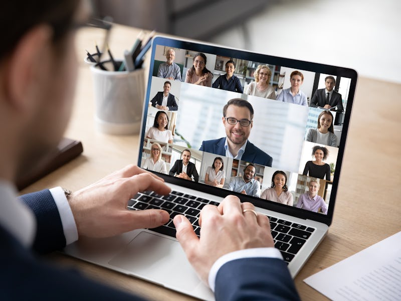 Rear view of businessman speak on web conference with diverse colleagues using laptop Webcam, male e...