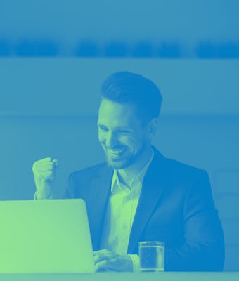 Happy young businessman in suit looking at laptop excited by good news online, lucky successful winn...