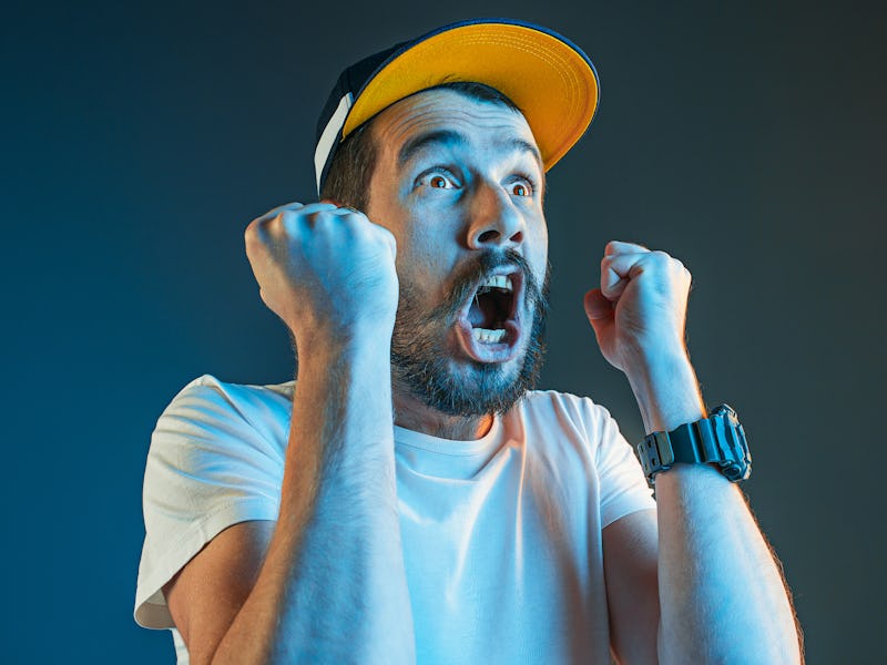 The anger and screaming man. Hate, rage. Crying emotional angry man in colorful bright lights at stu...