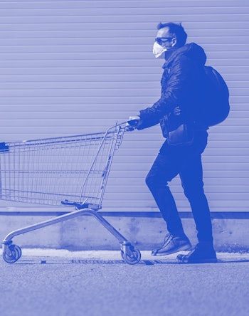 Man with with a shopping cart in front of a store, wearing a mask during a coronavirus pandemic / Co...