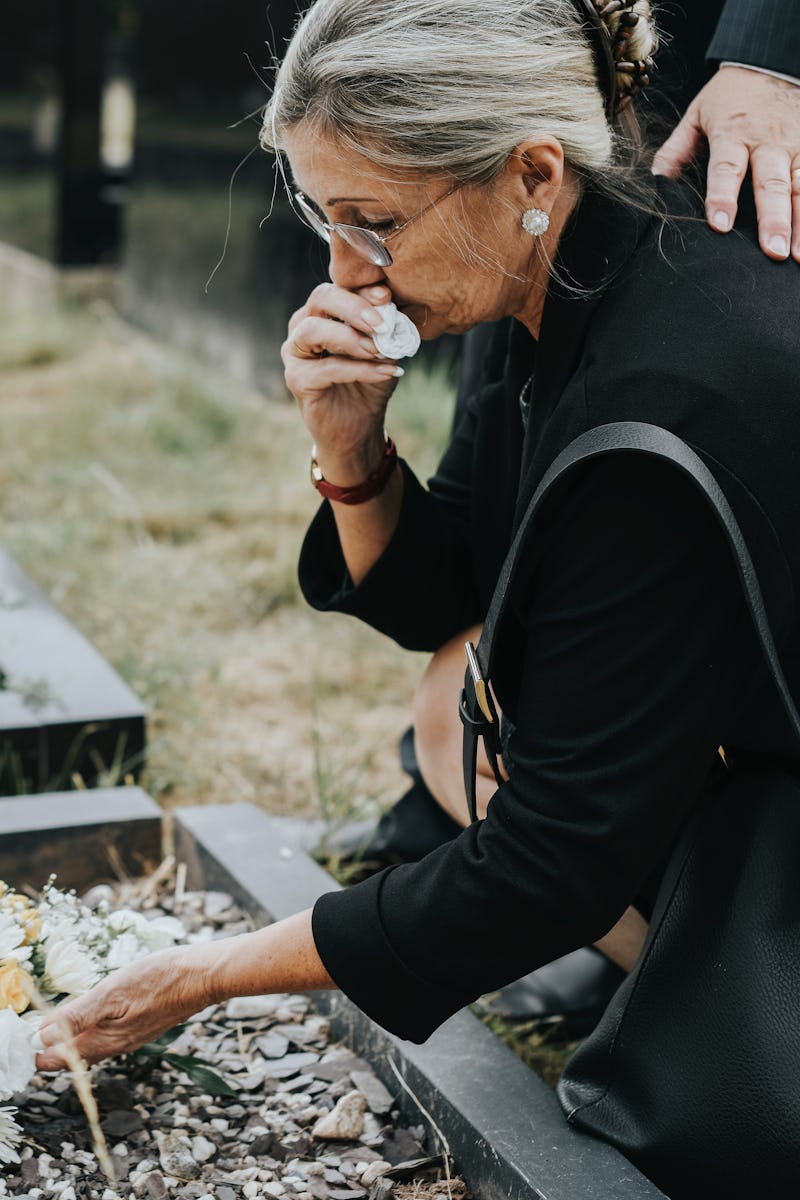 Old woman laying flowers on a grave