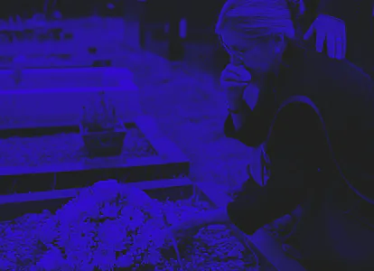 Old woman laying flowers on a grave