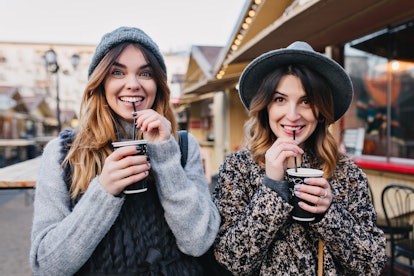 Portrait funny joyful attractive young women with drinks having fun on sunny street in city, smiling...
