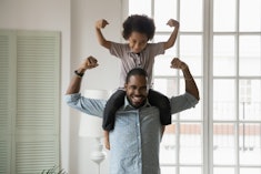 child posing as superhero on dad's shoulders