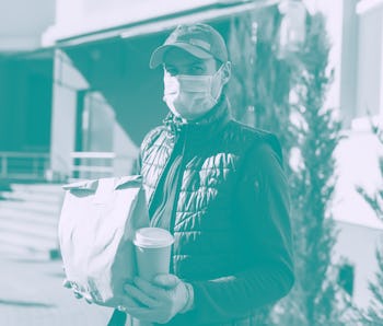 Courier in protective mask and medical gloves delivers takeaway food. Delivery service under quarant...