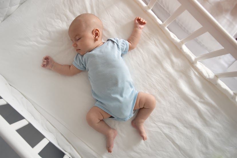 A baby asleep in a crib, an example of how sleep training and breastfeeding can work.