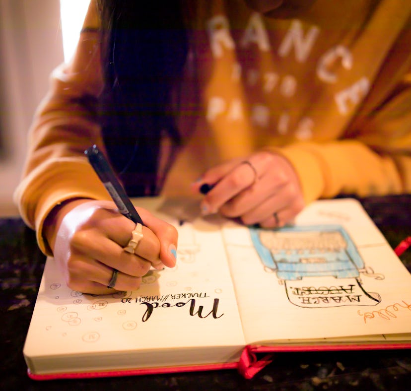 A woman writing in a 2022 bullet journal from Etsy on a mood tracker page.