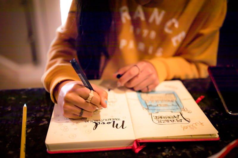 A woman writing in a 2022 bullet journal from Etsy on a mood tracker page.