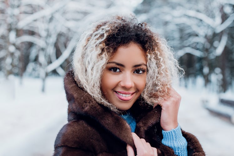 Smiling afro american girl wearing in fur coat in winter park