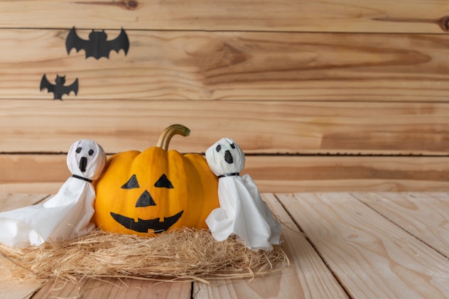 Front view of Halloween pumpkins, Yellow pumpkins ghost and paper ghost crafts on wooden wall backgr...