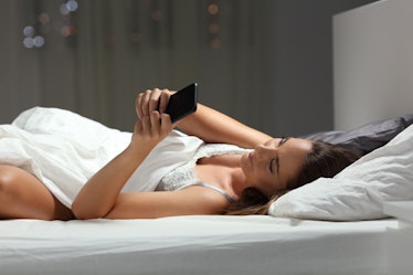 Libra woman lying in bed and texting her partner.