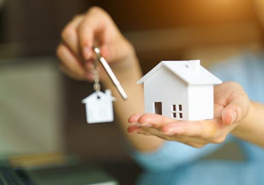Woman holding white house model and house key in hand.Mortgage loan approval home loan and insuranc...