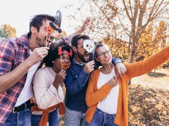 Group of young people hangout in the park.They are make selfie photo with halloween props.