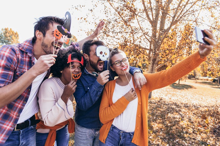 Group of young people hangout in the park.They are make selfie photo with halloween props.