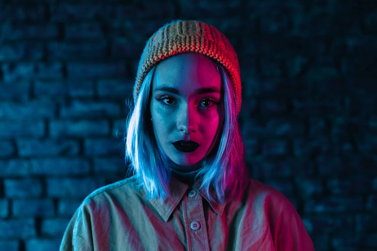 Young woman in pink and blue neon light. Portrait of unusual beautiful punk girl with colorful hairs...