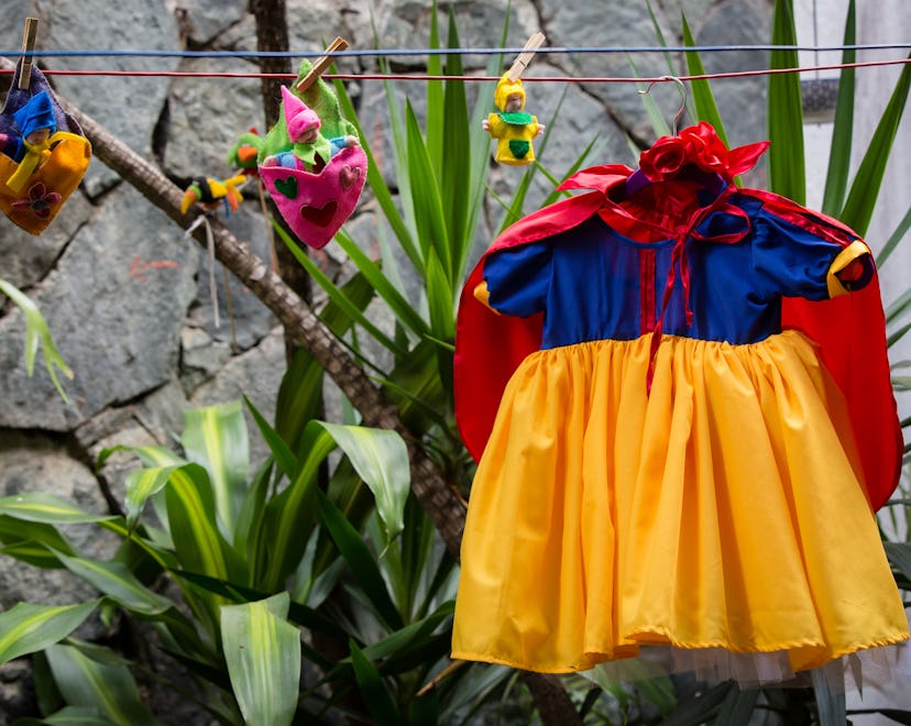 Concept: Trick or Treat. Getting ready for a kids costume party. Little snow whites dress hanging in...