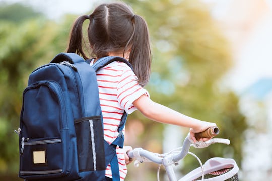 Back to school. Cute asian child girl with backpack biking a bicycle and going to school with fun