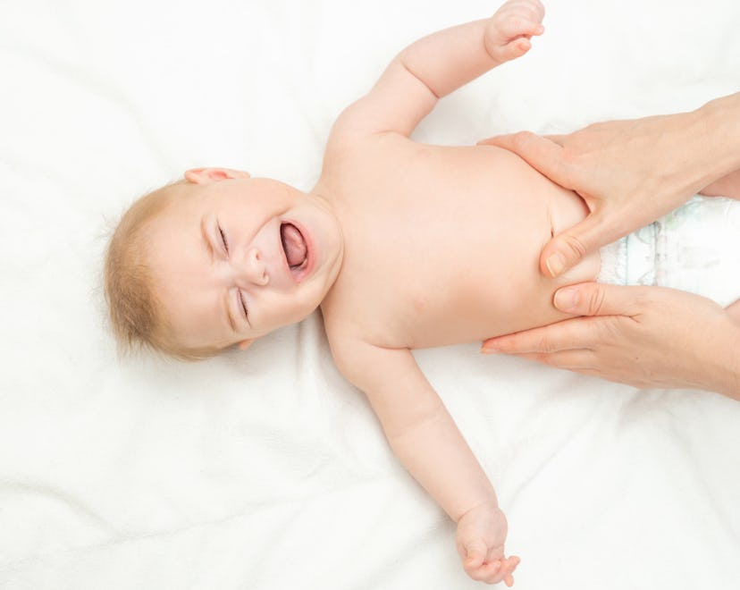 baby crying on bed getting their belly rubbed