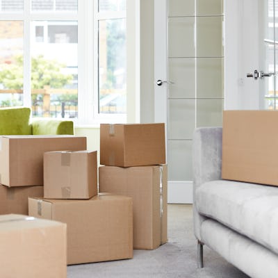 Cardboard carton boxes stack with household belongings in modern house living room. Packed container...