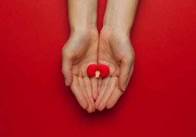 Hands hold a human kidney model on red background. Prevention of stones.