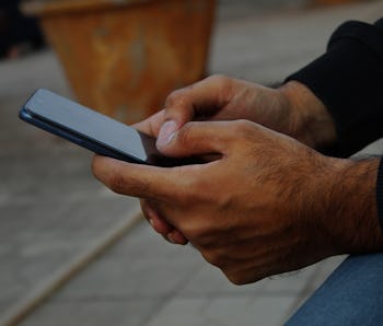 Closeup of middle aged dark skin man's hands using android pone