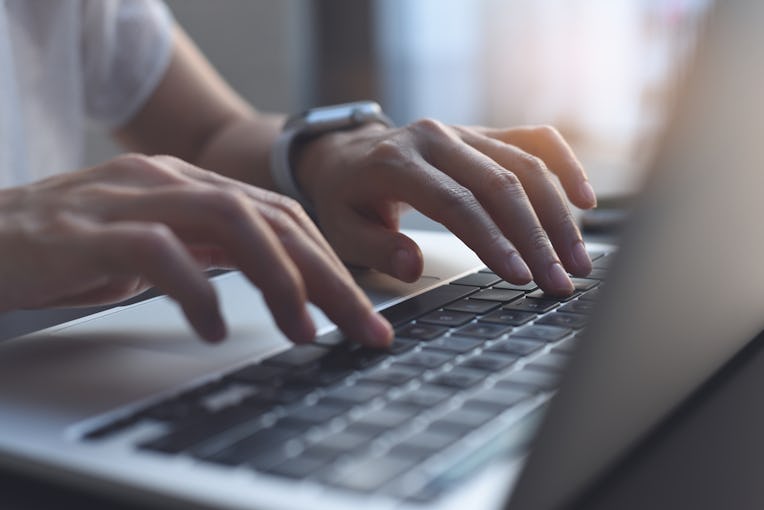 Close up image of woman hands typing on laptop computer keyboard and surfing the internet on office ...