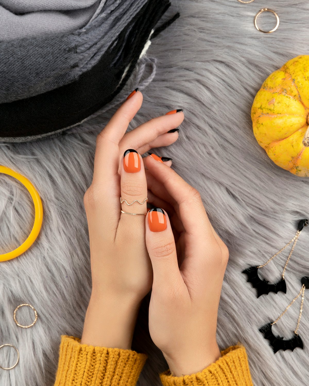 Manicured woman's hand with fаshion accessories over furry background. Trendy autumn halloween orang...