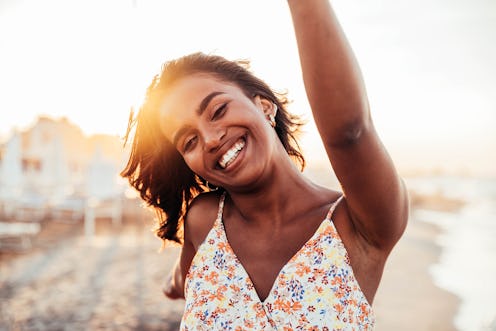 A cheerful woman smiling at the beach. Cancer zodiac sign strengths include being empathetic and com...