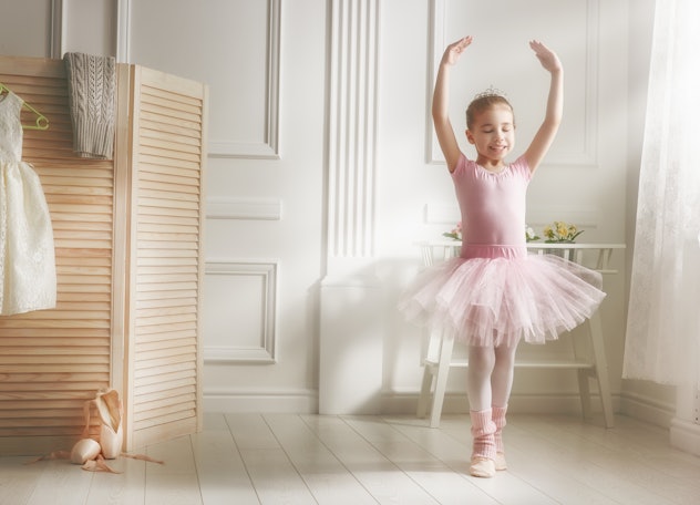 Cute little girl dreams of becoming a ballerina. Child girl in a pink tutu dancing in a room. Baby g...