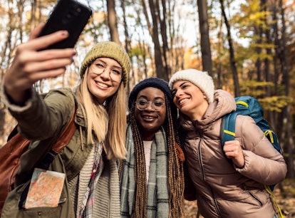 Three young women taking a photo during an autumn hike, thinking about how November 29, 2021 will be...