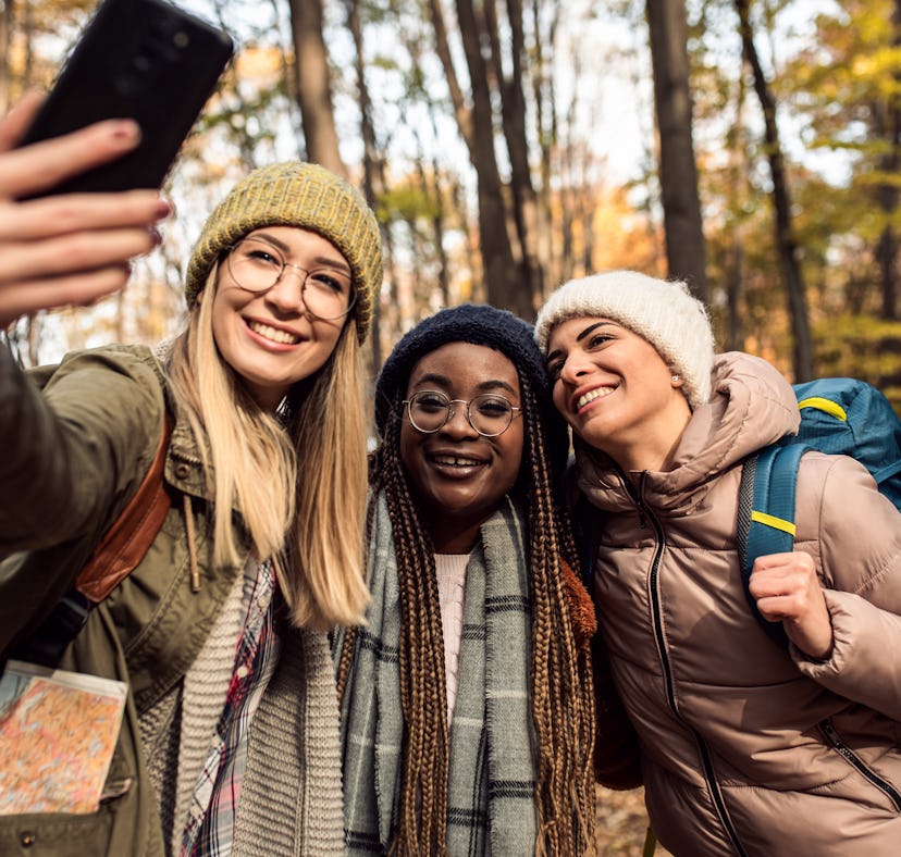 Three young women taking a photo during an autumn hike, thinking about how November 29, 2021 will be...