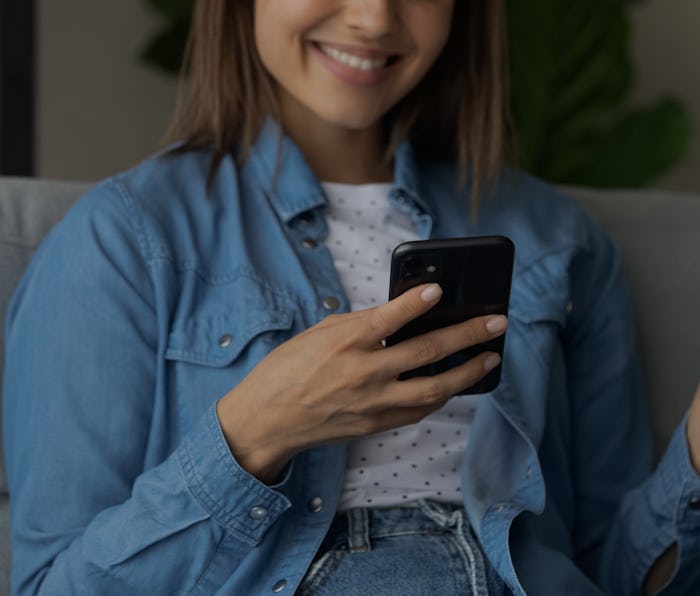 Close up young woman holding phone in hands, shopping in internet store, entering payment informatio...