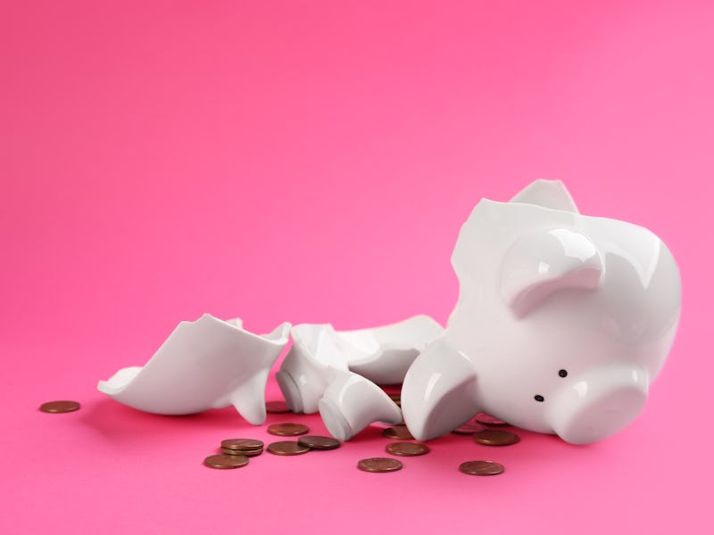 Broken piggy bank with coins on pink background