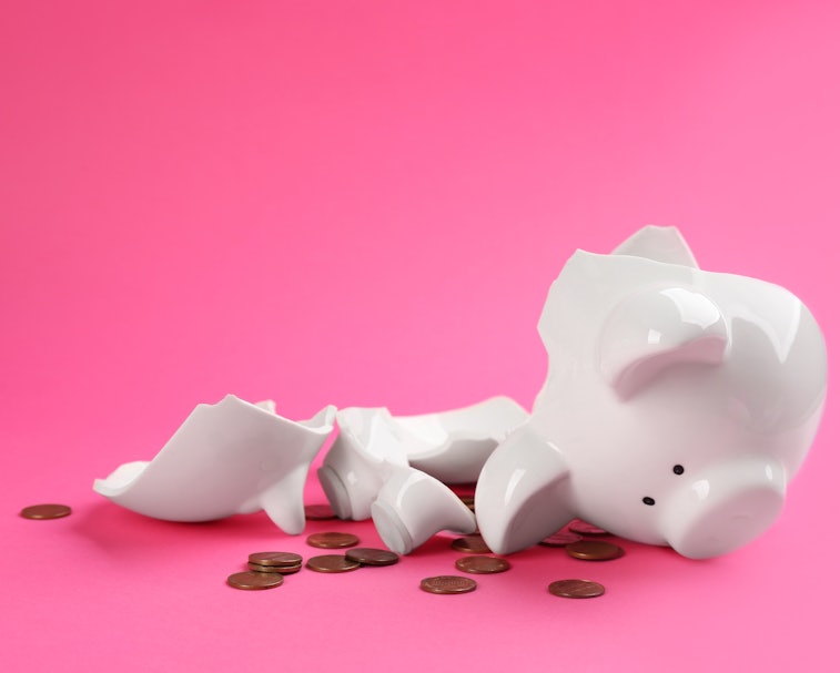Broken piggy bank with coins on pink background