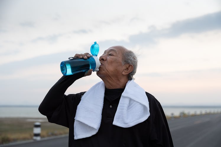 Close up Asian elderly drink water after exercise In the morning. health lifestyle and exercise Conc...