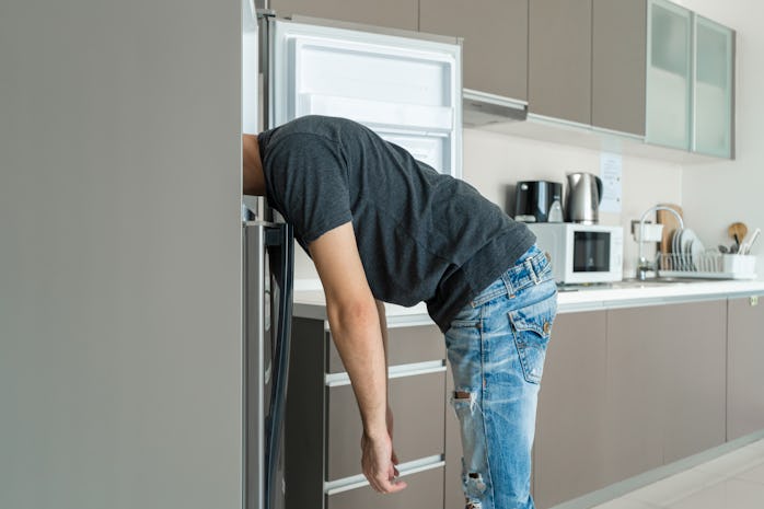 On a hot day, the guy cool down with his head in the refrigerator. Broken air conditioner.