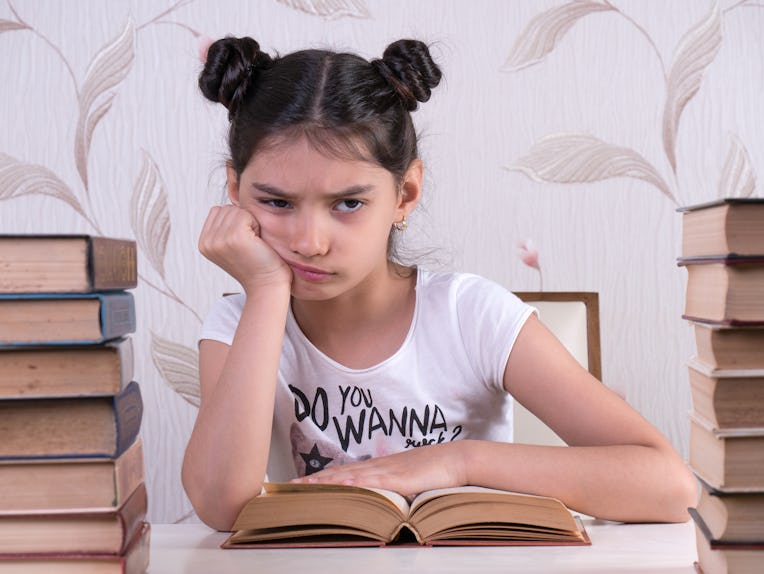 schoolgirl read book, young girl bored and tired of reading book at home. bored focused brainy girl ...