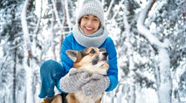 Winter smiling woman in warm hat and scarf hugging with her dog before reading her winter solstice 2...