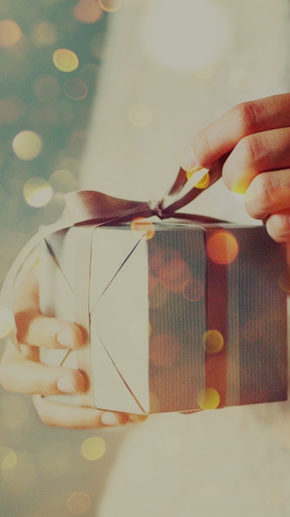 Shimmer background with snow, light bokeh. Woman hands opening gift box.