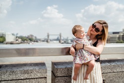 Mother with a daughter are staying and posing on the bridge in London.