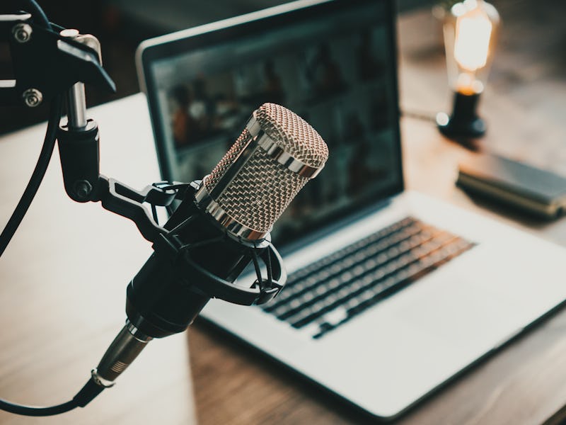 Home studio podcast interior. Microphone, laptop and on air lamp on the table, close-up