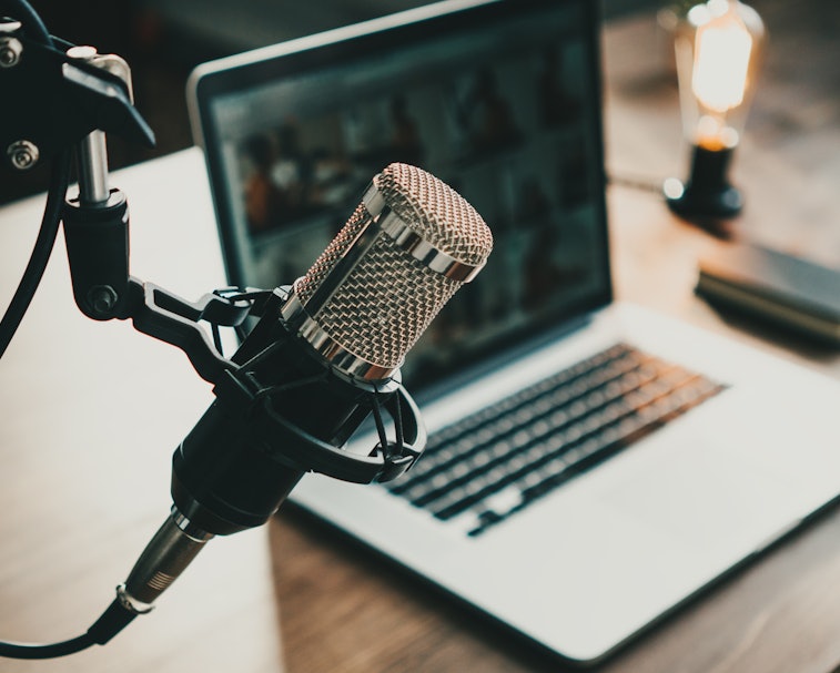 Home studio podcast interior. Microphone, laptop and on air lamp on the table, close-up