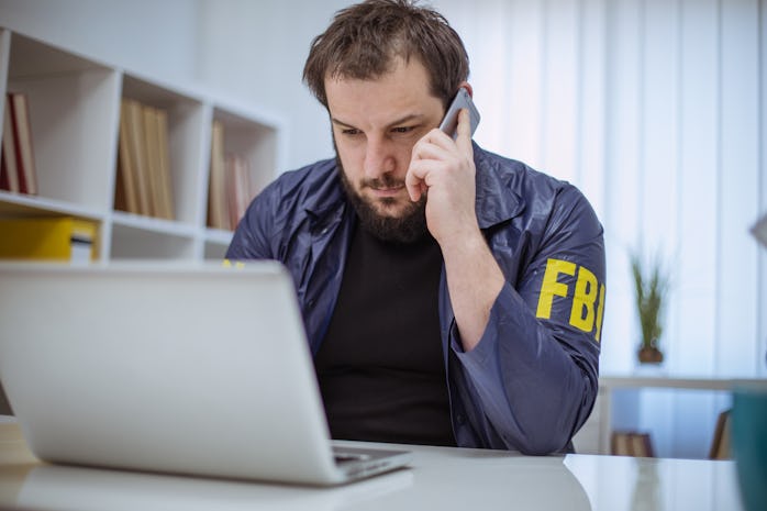 FBI agent working in his office on laptop and talking on mobile phone