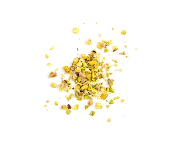 Scattered pistachio nut pieces isolated. Break chopped pistachios pile, fried baked diced pistache o...
