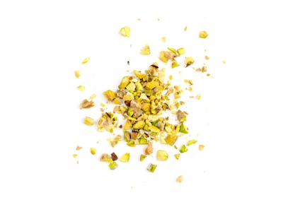 Scattered pistachio nut pieces isolated. Break chopped pistachios pile, fried baked diced pistache o...
