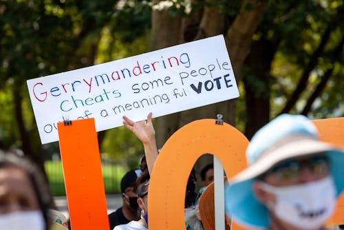 A protester holds a sign against gerrymandering during a voting rights rally at the White House.  Th...