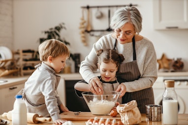 happy family grandmother and grandchildren cook in the kitchen, knead dough and bake cookies