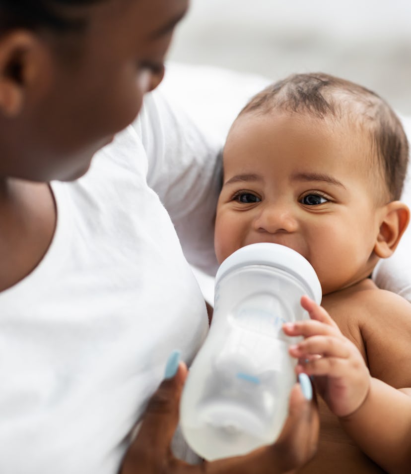 African American woman feeding her child from baby bottle