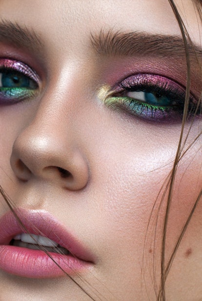 A very close up photo of young model with blue eyes, rainbow eyeshadows and perfect skin. Colorful e...