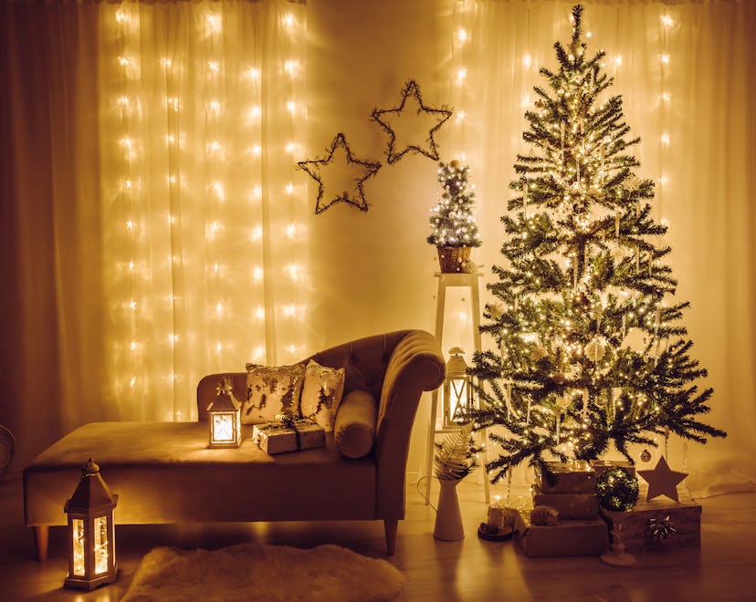 Home living room decorated for Christmas Eve. Christmas spruce tree decorated with party lights, ici...